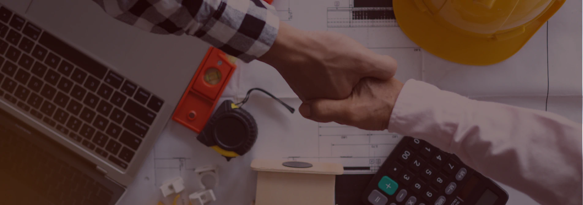 contractors shaking hands with his client over blue prints